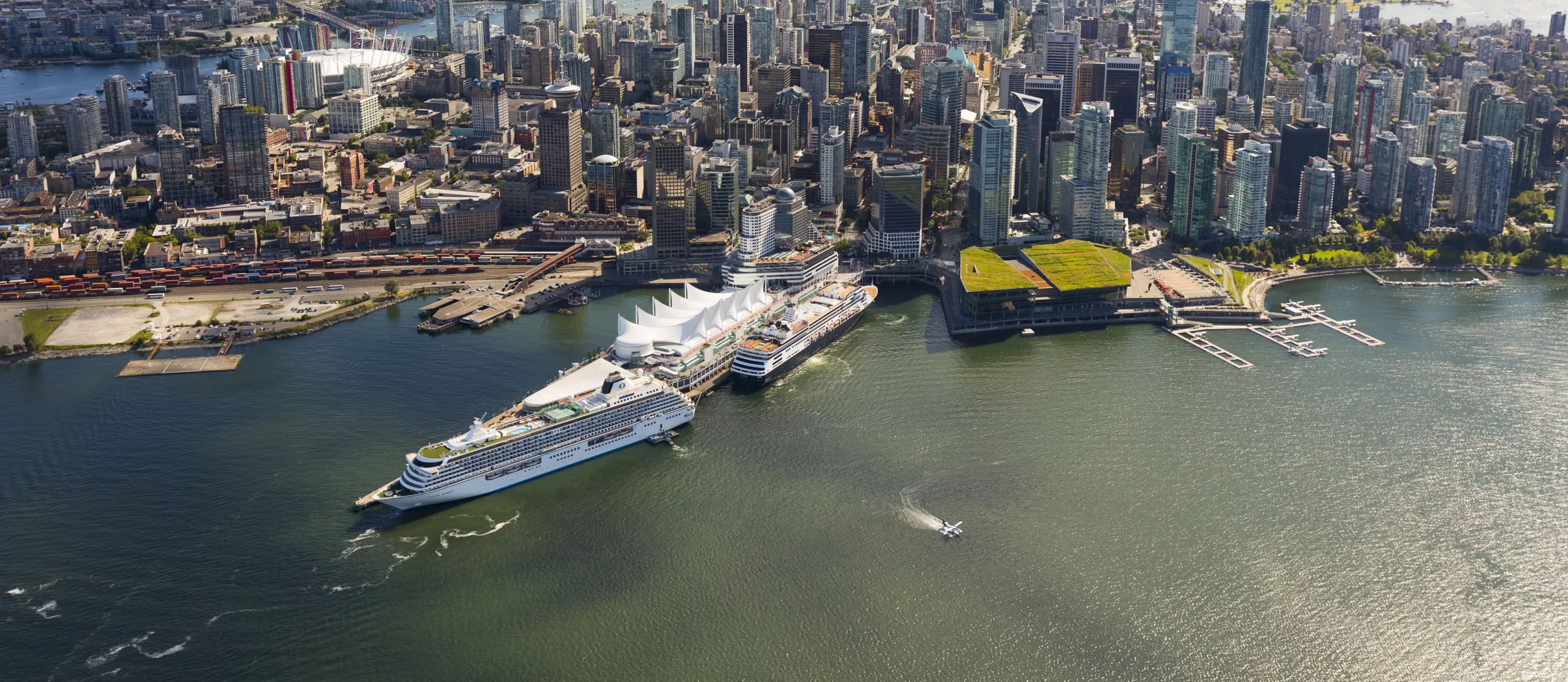 Vue aérienne de Vancouver, C.-B., Canada, montrant le centre-ville avec de nombreux gratte-ciel près du front de mer. Deux grands bateaux de croisière sont amarrés à Canada Place, un centre de congrès en forme de voile blanche.