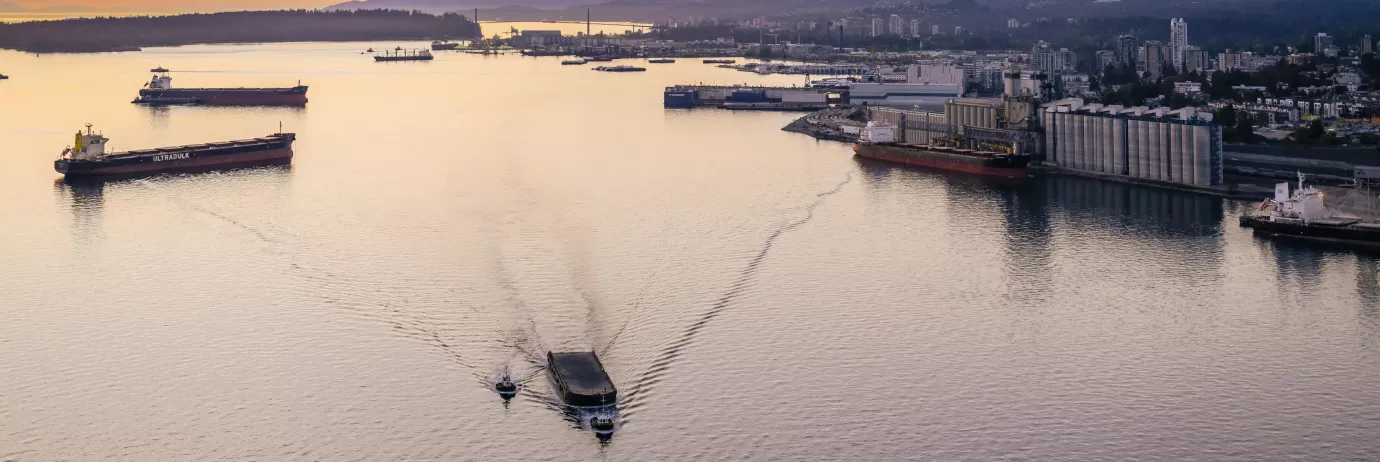 Burrard Inlet at sunset. Three ships can be seen in the water to the left. Vancouver's North Shore is visible to the right.